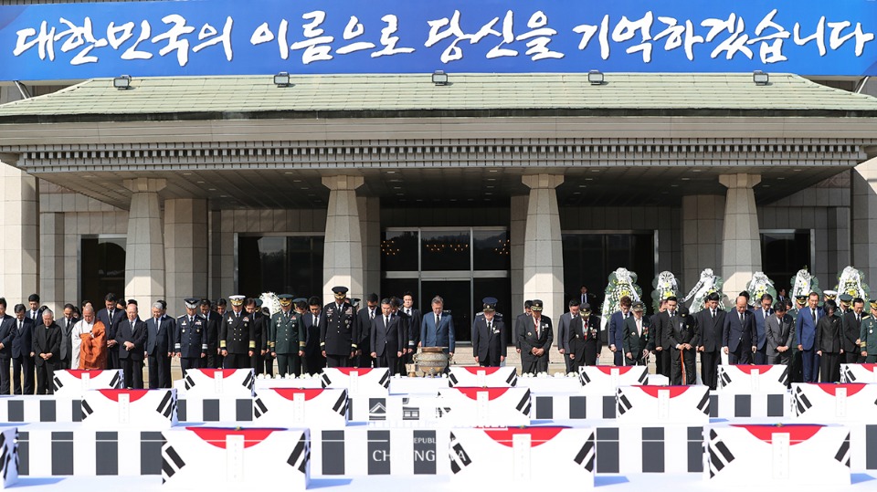 문재인 대통령이 제70주년 국군의 날인 1일 경기도 성남 서울공항에서 열린 국군 유해 봉환식에서 북한에서 돌아온 국군 유해 64위에 6·25 참전 기장을 수여한 뒤 묵념하고 있다.