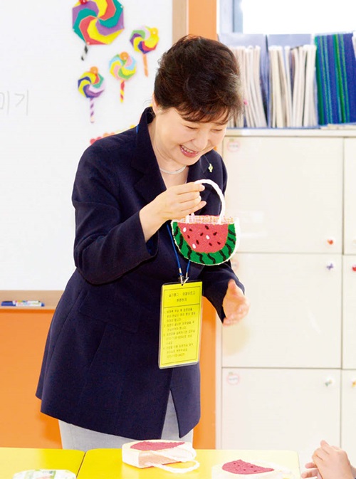 박 대통령이 6월 23일 서울 성북구 숭인초등학교의 초등돌봄교실 현장에서 한 어린이가 선물 한 점토로 만든 가방을 보고 있다