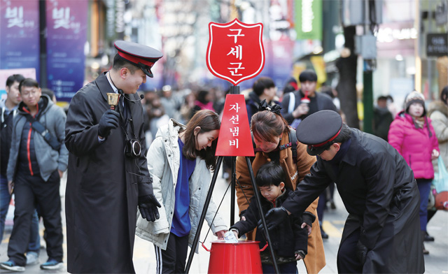 서울 중구 명동거리에서 시민들이 자선냄비에 성금을 기부하고 있다.