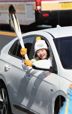 걸그룹 아이오아이 김소혜가 제주국제공항 앞 공항로에서 현대자동차의 아이오닉 전기차를 타고 성화를 봉송하고 있다.