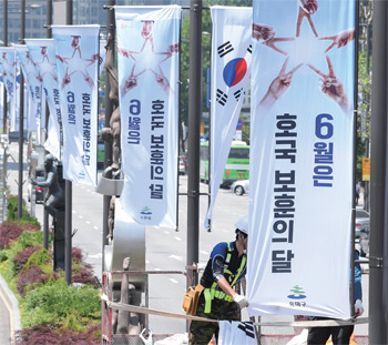 6월 호국보훈의 달을 하루 앞둔 5월 31일 서울 송파구 올림픽로에서 구청 관계자들이 호국보훈기와 태극기를 게양하고 있다.