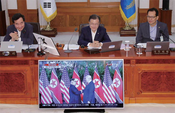 문재인 대통령이 6월 12일 청와대에서 국무회의에 앞서 김정은 국무위원장과 트럼프 대통령이 만나는 장면을 생중계로 지켜보며 미소짓고 있다.