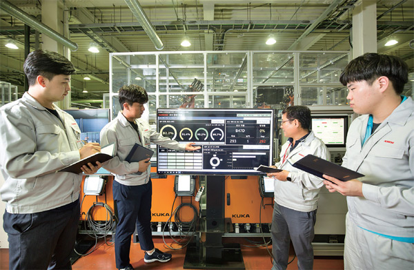가상현실 사이버물리시스템(VR CPS)’을 운용하는 작업장에서 생산기술본부 백동운 상무(오른쪽 둘째)가 직원들과 함께 작업상황판을 보며 작업공정을 체크하고 있다.