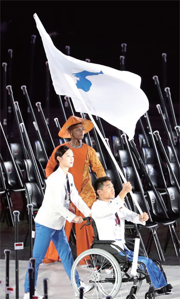 10월 6일(이하 현지 시간) 자카르타 겔로라 붕 카르노(GBK) 주 경기장에서 열린 2018 인도네시아 장애인아시안게임 개회식에서 휠체어펜싱 김선미, 수영 심승혁이 한반도기를 흔들며 입장하고 있다.