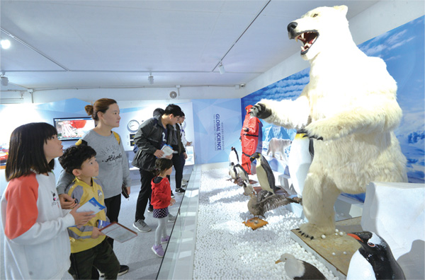 관광객들이 극지동물 모형을 구경하고 있다.
