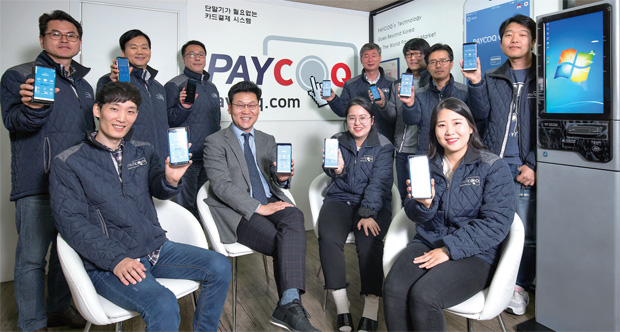권해원 페이콕 대표(앞줄 왼쪽에서 두 번째)와 페이콕 직원들이 스마트폰에 있는 페이콕 체크 앱을 들어 보이고 있다