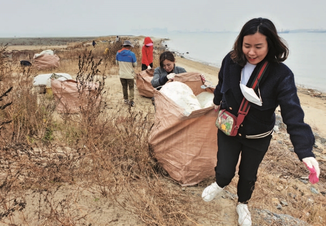 서천군 지속가능발전협의회 회원들이 바다 쓰레기를 담은 마대를 옮기고 있다. 남쪽 해변으로 넘어오는 다리가 좁아 사람이 직접 마대를 날라야 한다.