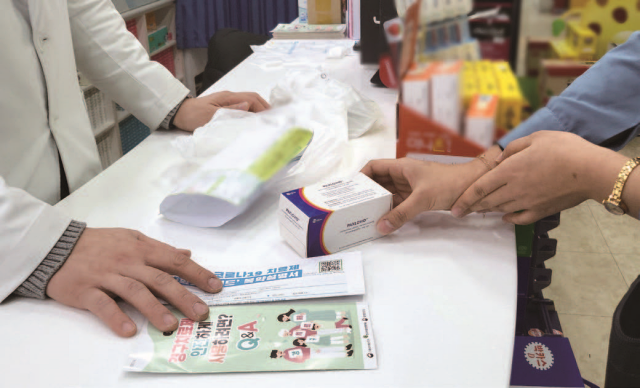 코로나치료제 담당약국에서 한 보건소 직원이 먹는 코로나19 치료제 팍스로비드를 전달받고 있다. 사진 뉴시스