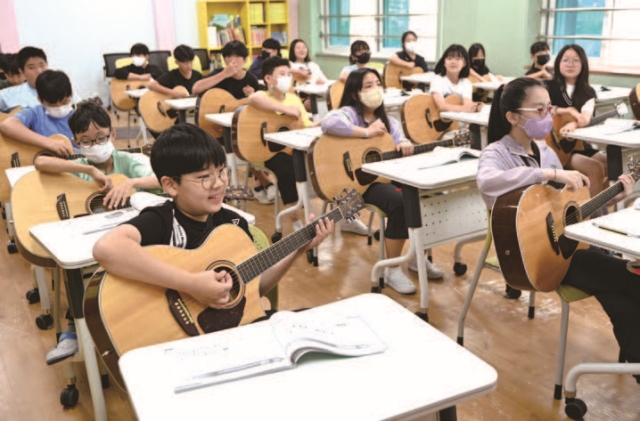 경기 오산시 원동초등학교 스포츠센터에서 어린이들이 통기타 실기교육을 받고 있다. 사진 뉴시스