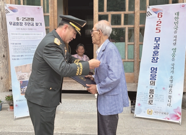 신기진 조사단장이 무공훈장 수훈자에게 훈장을 전해주고 있다. 사진 625무공훈장 주인공 찾아주기 조사단