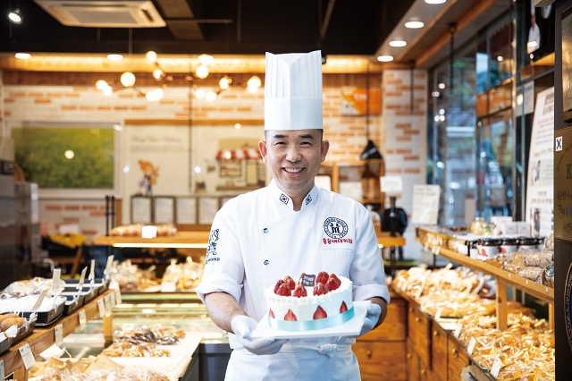 홍윤베이커리 홍동수 대표. 손에 든 딸기생크림케이크는 가루쌀로 만든 제품이다. 사진 C영상미디어