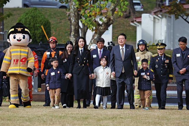 윤석열 대통령과 부인 김건희 여사가 11월 9일 서울 용산어린이정원 잔디마당에서 열린 &lsquo;제61주년 소방의 날 기념식&rsquo;에 순직 소방관 자녀들과 손을 잡고 함께 입장하고 있다. 사진 뉴시스
