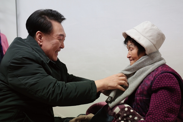 윤석열 대통령이 12월 21일 서울 중랑구 한 다세대주택을 찾아 독거 어르신의 안부를 살피고 목도리를 둘러드리고 있다. 사진 대통령실