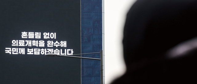 전공의들의 의료현장 이탈이 장기화되는 가운데 3월 12일 서울시내 한 건물 외벽 전광판에 정부의 ‘의료개혁 완수’ 광고가 나오고 있다. 사진 뉴시스