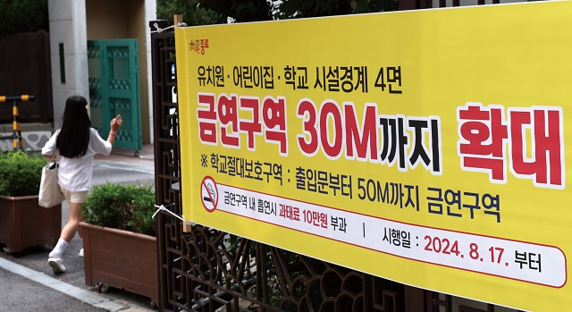 7월 31일 서울 종로구의 한 초등학교 앞에 ‘8월 17일부터 유치원·어린이집·학교 시설경계 4면 금연구역 30M까지 확대’라고 적힌 현수막이 부착돼 있다. 사진 뉴시스