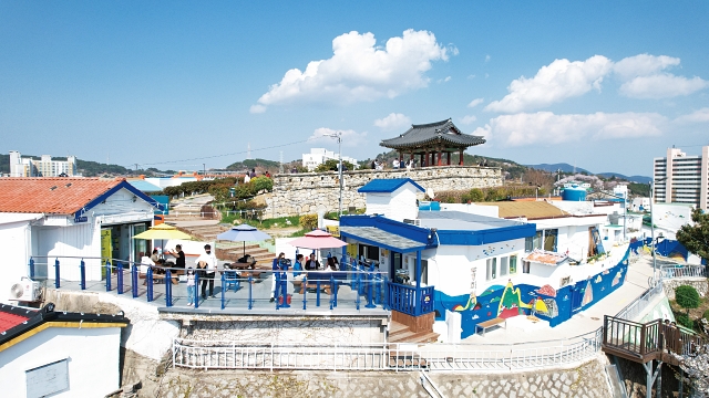 동피랑 벽화마을 꼭대기에 자리잡은 동포루와 벽화 가득한 골목·카페에서 여행객들이 여유를 즐기고 있다. 사진 통영시청