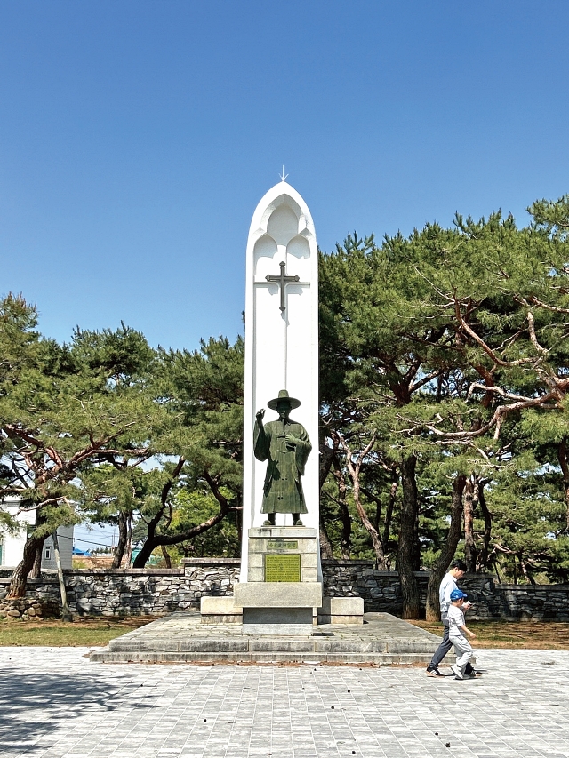 울창한 소나무 숲이 감싸고 있는 김대건 신부의 동상.
