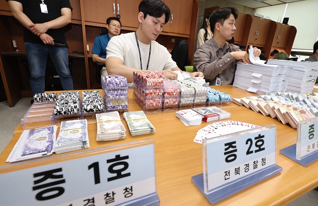 전북경찰청 형사기동대 경찰들이 2024년 6월 27일 전북 전주시 전북경찰청 기자실에서 홀덤펍 업주 구속(도박, 장개설, 환전) 사건 브리핑을 열고 압수품을 정리하고 있다. 사진 뉴시스