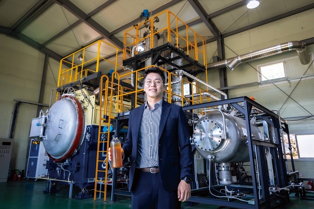 에코인에너지 이인 대표가 ‘이동 가능한 모듈형 IoT 폐플라스틱 열분해 장치’에서 뽑아낸 열분해유를 들고 있다. 사진 C영상미디어