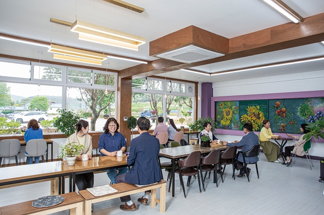 교실 두 칸을 합쳐 리모델링한 카페의 내부 모습. 한쪽 벽면은 칠판을 캔버스로 활용해 지역 출신 작가의 작품을 선보이고 있다. 사진 C영상미디어