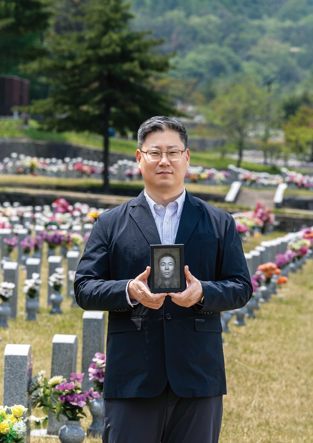 국방부 유해발굴감식단 이규상 중앙감식소장이 6·25 전사자 얼굴 복원 프로젝트 1호 송영환 일병의 영정을 들고 있다. 사진 C영상미디어