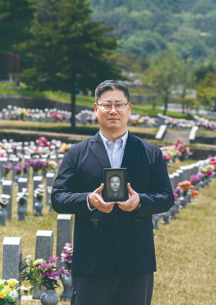 국방부 유해발굴감식단 이규상 중앙감식소장이 6.25 전사자 얼굴 복원 프로젝트 1호 송영환 일병의 영정을 들고 있다. 사진 C영상미디어
