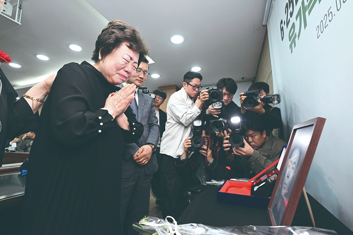 송재숙 씨가 아버지 송영환 일병의 영정 앞에 하얀색 카네이션을 바치고 손을 모으고 있다. 송 씨는 5년 전 유가족 유전자 시료 채취에 참여한 덕분에 아버지 얼굴을 마주할 수 있었다. 사진 국방부 유해발굴감식단