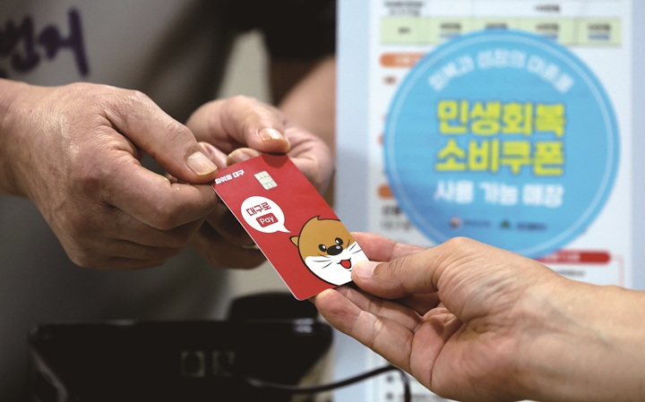 '민생회복 소비쿠폰'신청 이틀째인 7월 22일 대구 중구 한 음식점에서 식사를 마친 시민이 소비쿠폰이 입금된 선불카드로 결제하고 있다. 사진 뉴시스