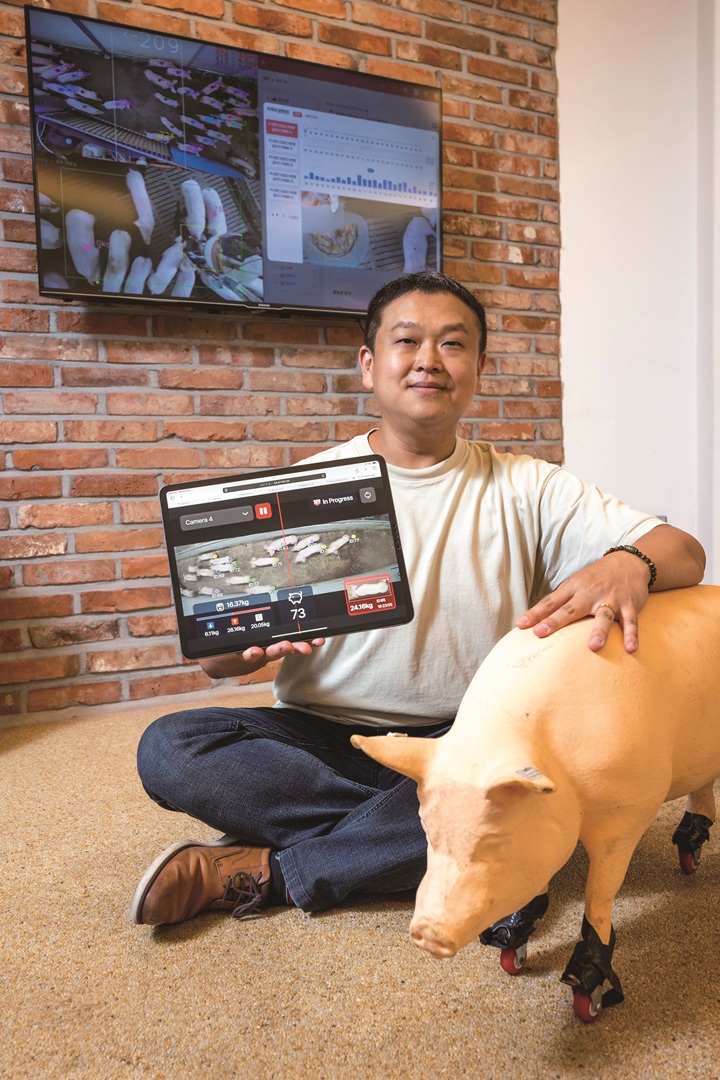 인공지능(AI)을 활용한 '비접촉 체중 측정 기술'은 돼지의 건강상태와 상품성을 파악할 수 있다. 전광명 대표가 한 돼지 농장의 현황을 실시간으로 전달하는 모니터를 들고 있다. 사진 C영상미디어