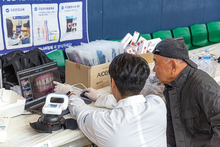 구강관리 검사 부스에서 어르신이 치아 상태를 확인하고 있다.
