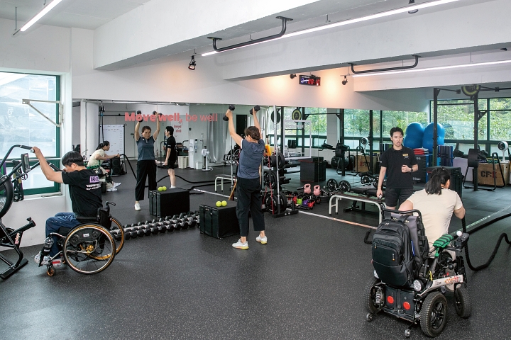 휠체어 이용자와 비장애인이 각자의 신체 조건에 맞춘 동작을 수행하며 한 공간에서 함께 운동하고 있다. 사진 C영상미디어