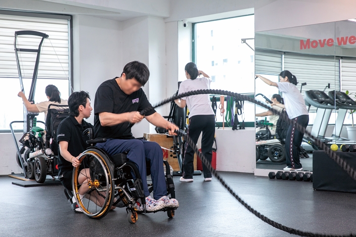 휠체어 이용자가 상체 중심의 동작으로 배틀로프 운동을 하고 있다.