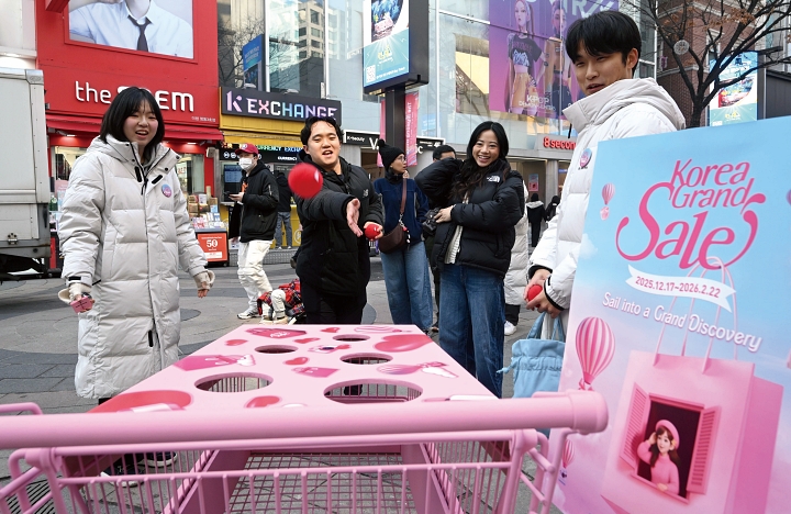 2025년 12월 서울 중구 명동거리 일대에서 관광객들이 코리아그랜드세일 홍보 부스를 체험하고 있다. 사진 뉴시스