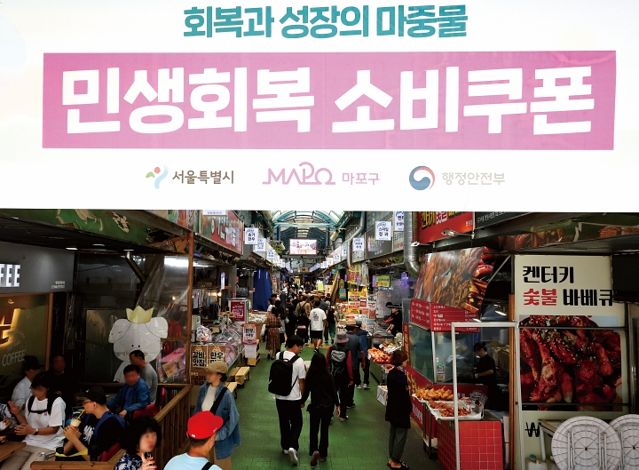 &lsquo;민생회복 소비쿠폰&rsquo; 사용 가능 안내문이 게시된 서울 시내 전통시장. 정부는 2025년 전 국민에게 13조 5000억 원 규모의 소비쿠폰을 지급했으며 사용률은 99.8%를 기록했다. 사진 뉴시스