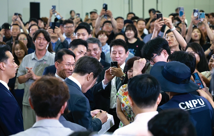 이재명 대통령이 2025년 7월 4일 대전컨벤션센터에서 열린 &lsquo;충청의 마음을 듣다&rsquo; 타운홀 미팅에 입장하던 중 참석자의 요청으로 책자에 서명하고 있다. 사진 청와대
