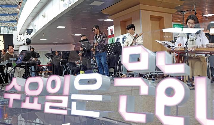 최휘영 문화체육관광부 장관(가운데)이 4월 1일 &lsquo;문화가 있는 날&rsquo;의 매주 수요일 확대 시행을 기념해 서울역에서 열린 &lsquo;수요일은 문화요일, 문화로 놀자!&rsquo; 공연에 참여해 기타를 연주하고 있다. 사진 문화체육관광부
