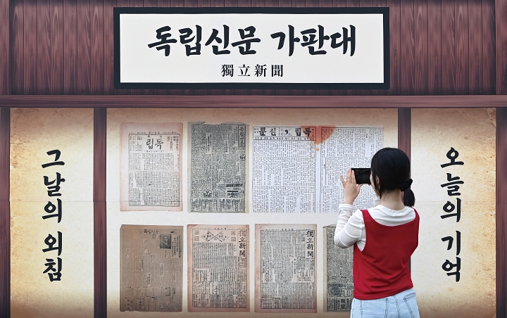 지난 6월 경기 수원시 화성행궁에서 열린 ‘메모리얼 테마파크 기억의 광장’에서 한 시민이 독립신문 가판대를 살펴보고 있다. 사진 뉴시스