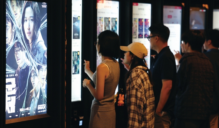 6월 서울 시내 한 영화관에서 청년들이 관람할 영화를 고르고 있다. 사진 뉴시스