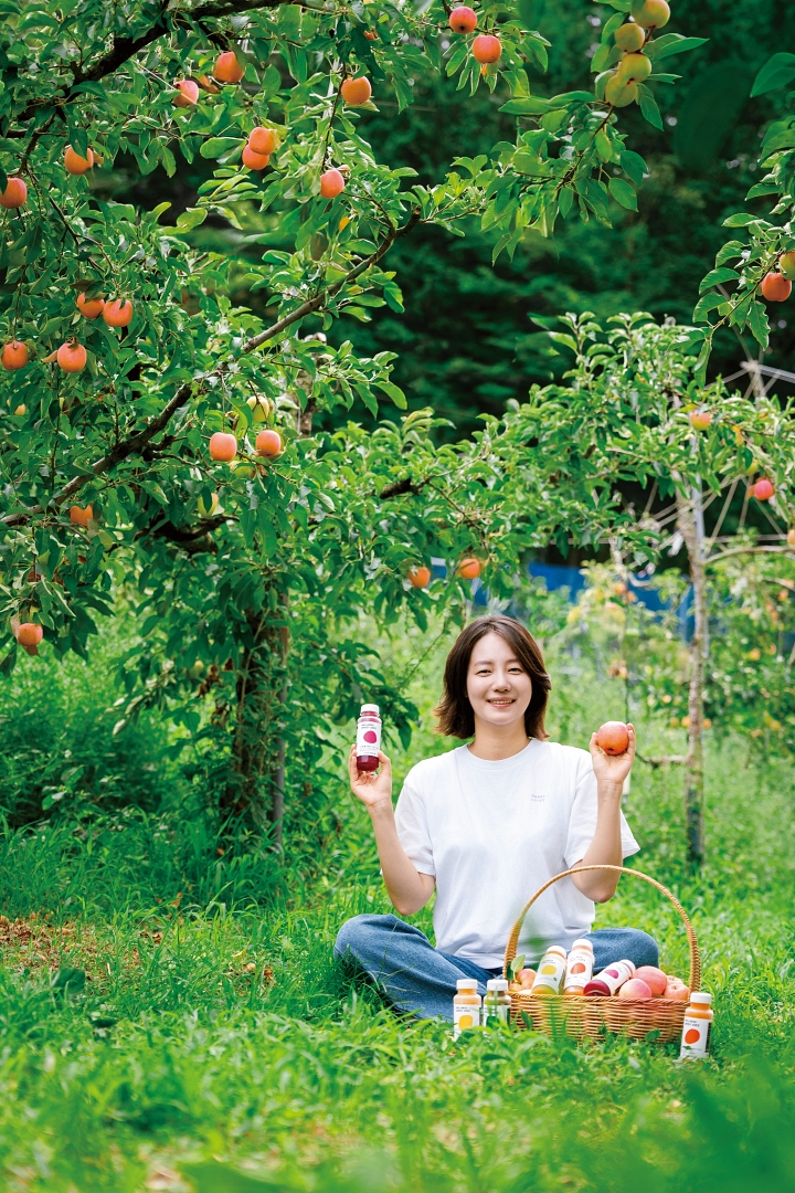&lsquo;오롯이&rsquo; 최연희 대표가 전남광주통합특별시 장성군의 한 사과밭에서 방금 딴 사과와 주스를 들고 있다. 최 대표는 지역 농가의 못난이 과일&middot;채소 등으로 주스를 만들어 판매한다. 사진 C영상미디어