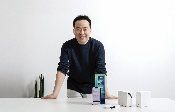 망고슬래브 정용수 대표가 네모닉 닷 애플리케이션에 &lsquo;케이공감&rsquo;이라고 쓴 뒤 이를 보여주고 있다. 정 대표 옆으로 네모닉 닷과 네모닉 닷 안에 넣어 쓰는 카트리지가 놓여 있다. 사진 C영상미디어