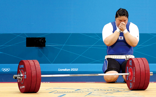 메달 획득에 실패한 장미란이 역기 앞에서 무릎을 꿇고 기도하고 있다.