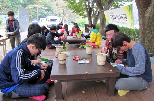 자신이 가져온 식물이 어떤 것이지 열심히 식물도감을 찾고 있는 나눔의 숲 참가 학생들.