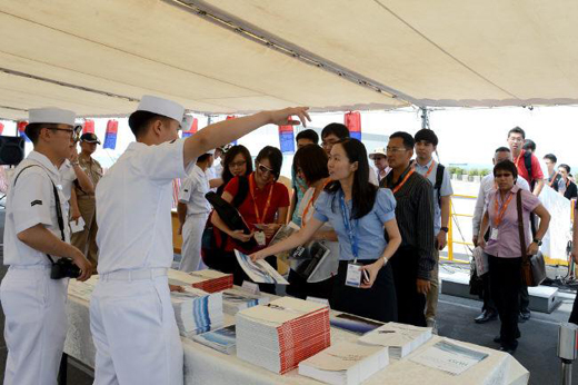 청해부대 13진 왕건함 장병들이 지난 15일 함정 공개 행사에서 싱가포르 국제해양방산전시회 관람객들에게 국내 방산업체 홍보 책자를 나눠 주고 있다.(사진=국방일보)