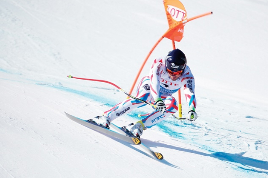 FIS 스키 월드컵에서 한 선수가 빠르게 활강 코스를 내려오고 있다.