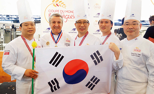 올해 제빵 월드컵에서 사상 처음으로 우승을 차지한 한국 팀과 심사위원이 기념 촬영을 하고 있다. 왼쪽부터 박용주, 가운데 김종호, 오른쪽 두 번째 이창민 제빵사.
