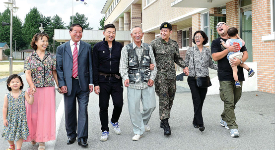 4대가 병역을 이행한 이영일(왼쪽 다섯째) 옹의 가족이 육군2군단 헌병대에서 근무하는 손자 이진호(왼쪽 여섯째일병의 부대를 방문해 함께 걸으며 이야기를 나누고 있다. 왼쪽부터 영혜 씨 손녀, 영혜 씨, 영달 씨, 이일병의 아버지 성규 씨, 이옹, 이 일병, 영란 씨, 영란 씨 아들, 영혜 씨 손자.