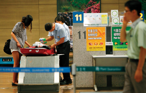 인천공항 검색대에서 관세청 직원이 승객들의 수하물과 휴대용 가방을 살펴보고 있다.