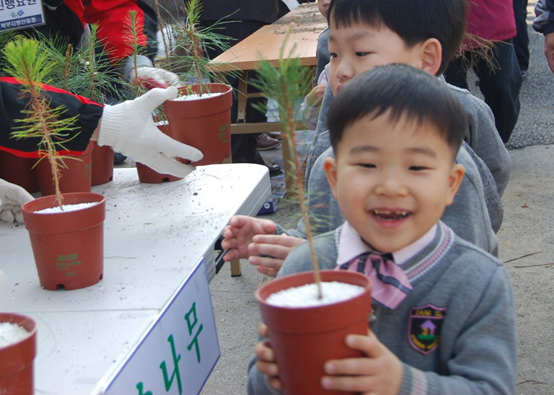 내나무 갖기 캠페인에서 한 아이가 나무를 받아들고 해맑게 웃고 있다. <저작권자(c) 연합뉴스, 무단 전재-재배포 금지> 