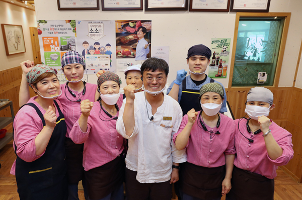 박영아 대표와 마스크와 두건, 앞치마를 갖추고 일하는 직원들이 파잇팅을 외치고 있다. 