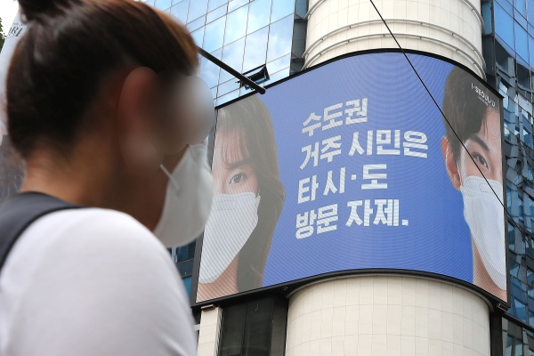 23일 서울 중구 명동거리에서 한 시민이 전광판에 나오는 마스크 쓰기 캠페인 화면 앞을 지나고 있다. (출처=news1)